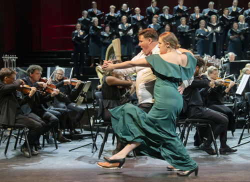 Kvinne i grønn kjole og mann danser tango foran orkester